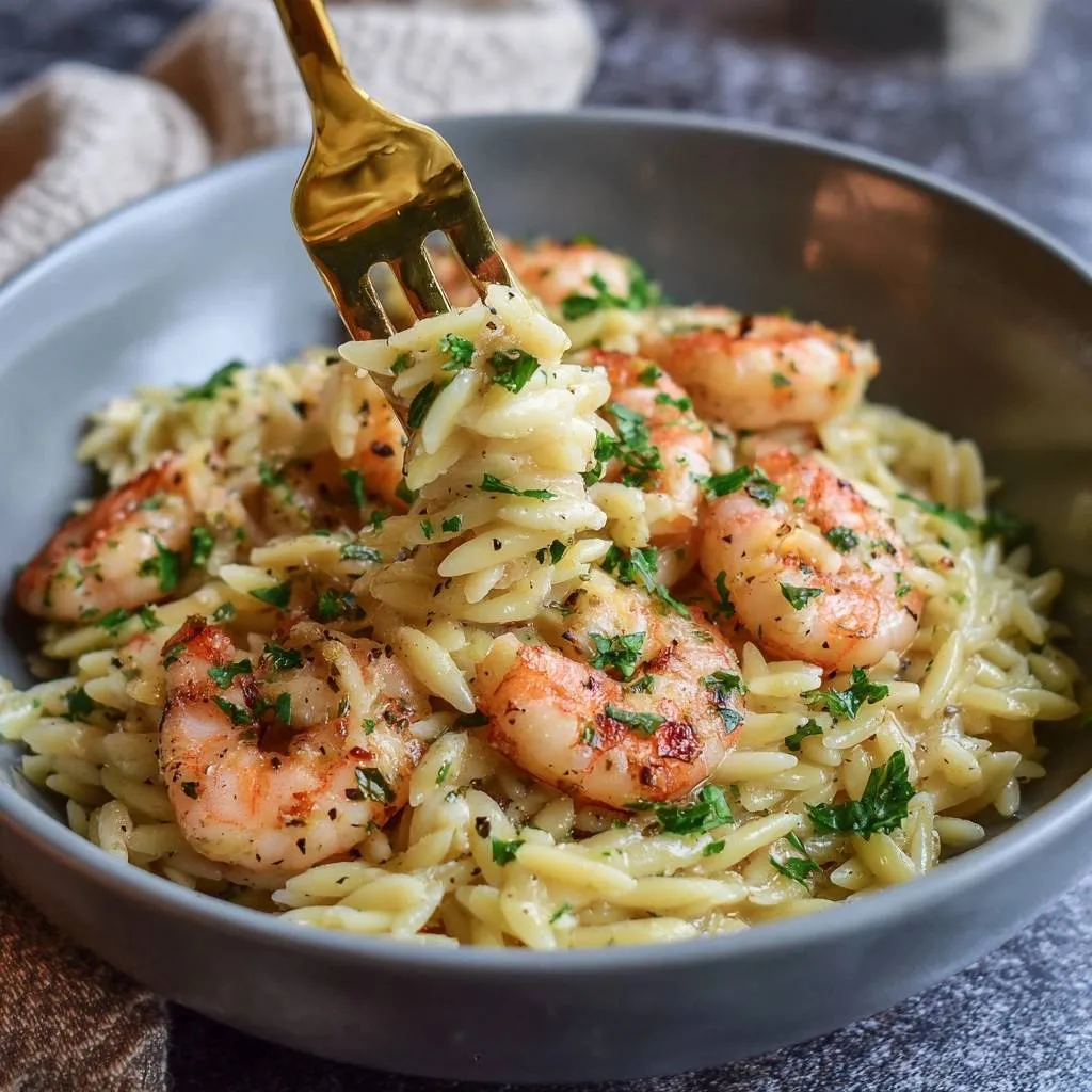 Garlic butter shrimp orzo with a fork lifting a portion, garnished with parsley.