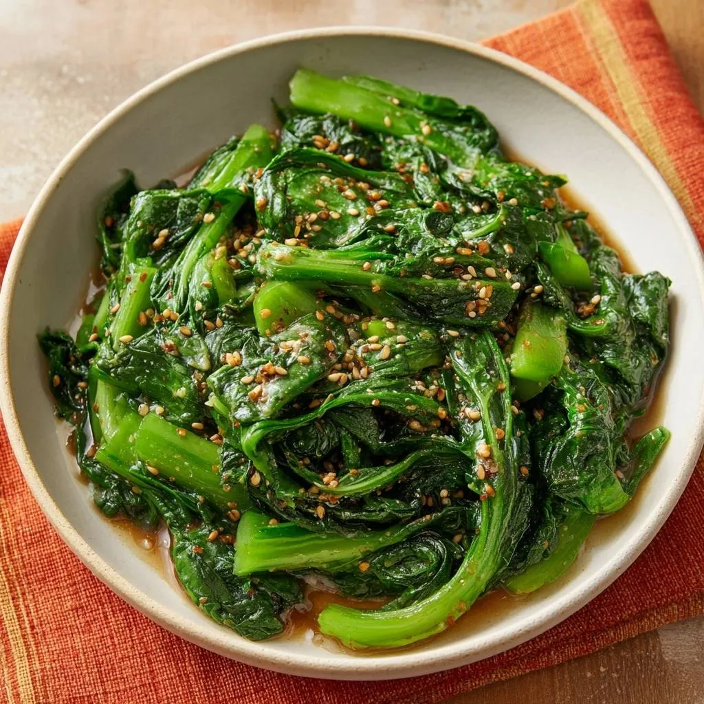 Sesame bok choy stir-fry in a bowl, glistening with sauce and sprinkled with sesame seeds.