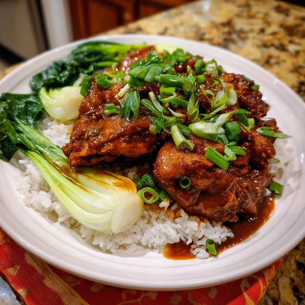 Soy glazed chicken with bok choy and rice, a plated serving generously garnished with chopped green onions.