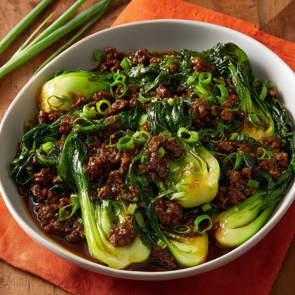 Beef bok choy stir-fry in a white bowl, garnished with chopped green onions and featuring tender bok choy leaves.