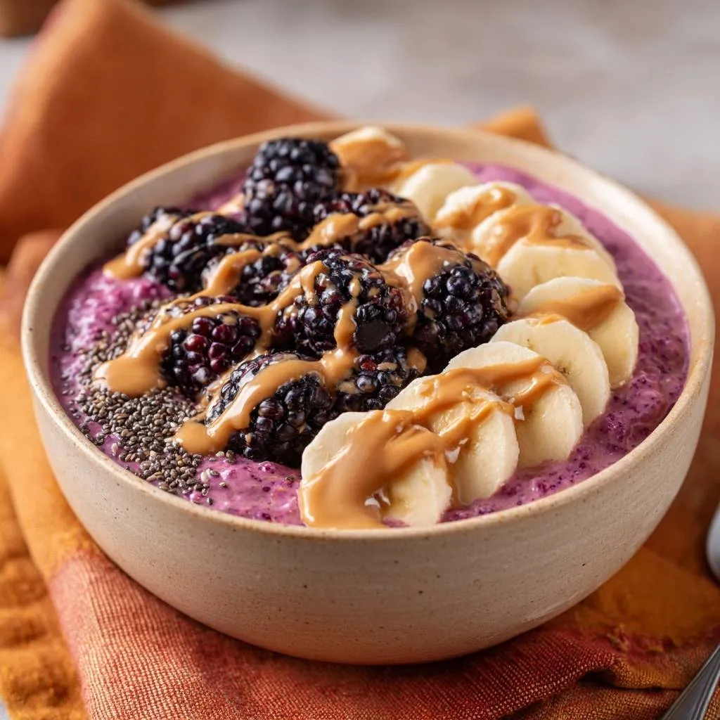 Blackberry Peanut Butter Oat Bowl drizzled with creamy peanut butter and topped with fresh blackberries and banana slices.