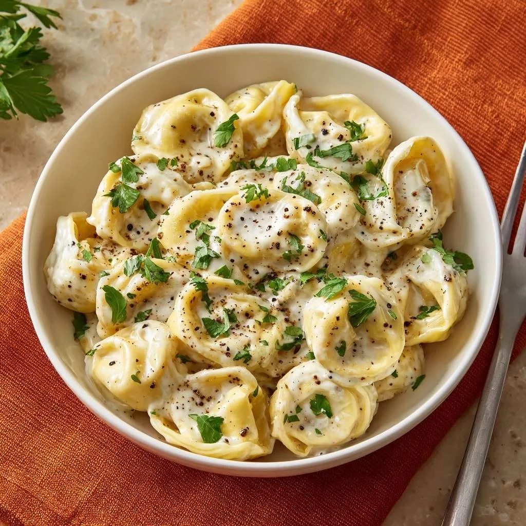 Ultra creamy pepper ravioli served in a white bowl, viewed from directly overhead and garnished with fresh parsley.