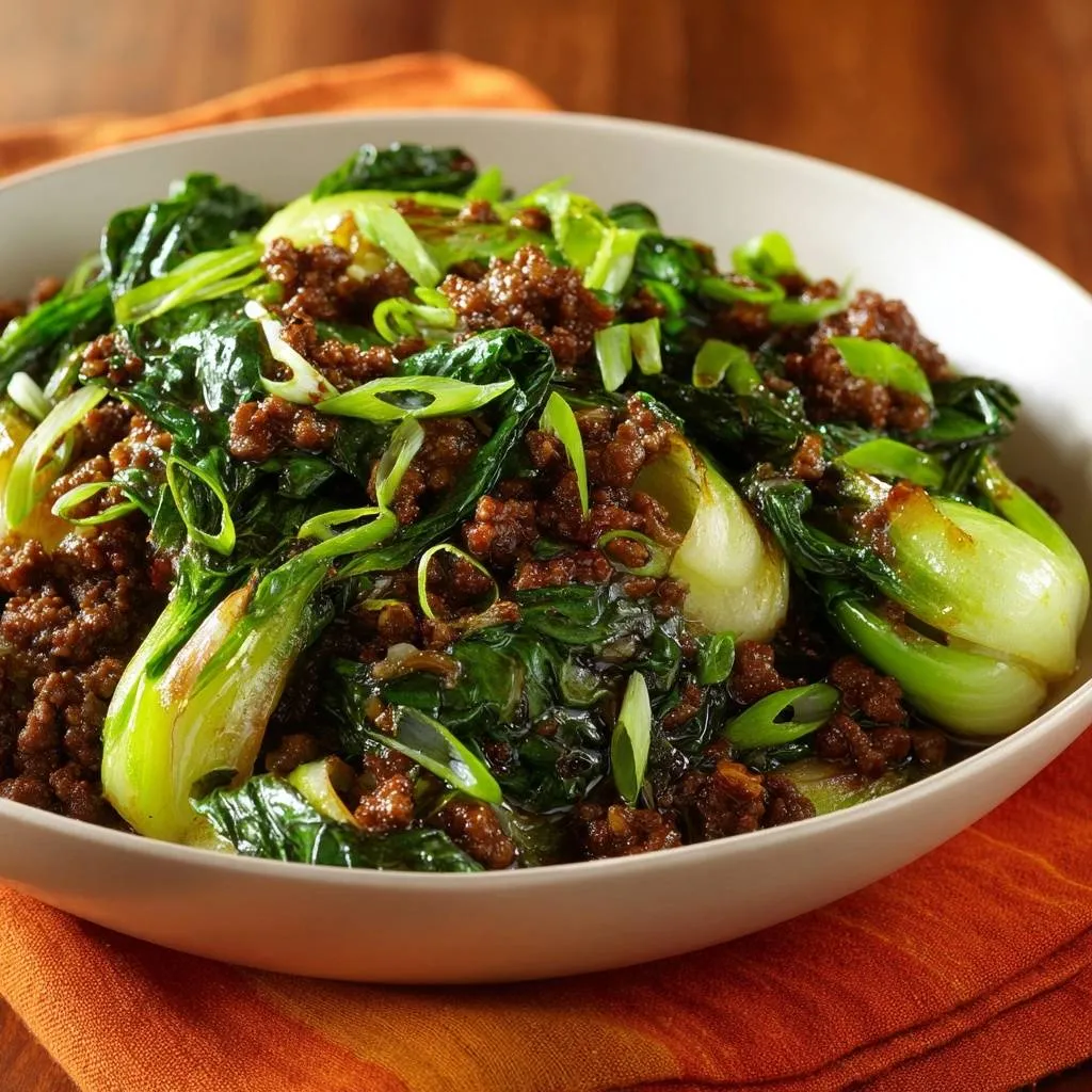 Savory beef and bok choy stir-fry in a white bowl, garnished with sliced green onions, a close-up view.