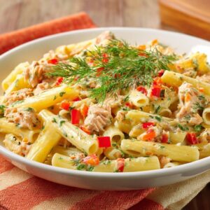 Creamy salmon and dill penne with a non-watery sauce, shown in a close-up view with a fresh dill garnish.